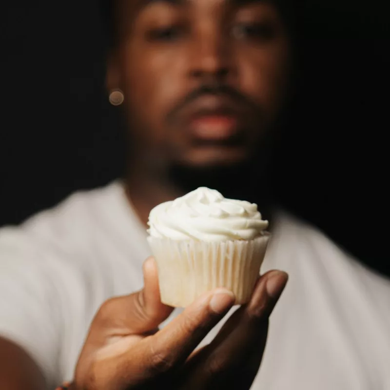 The founder, Mike, holding a cupcake up close.