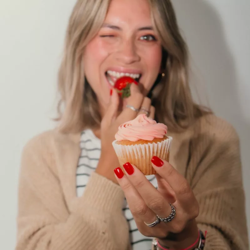 A healthy mom enjoying a strawberry cupcake. 